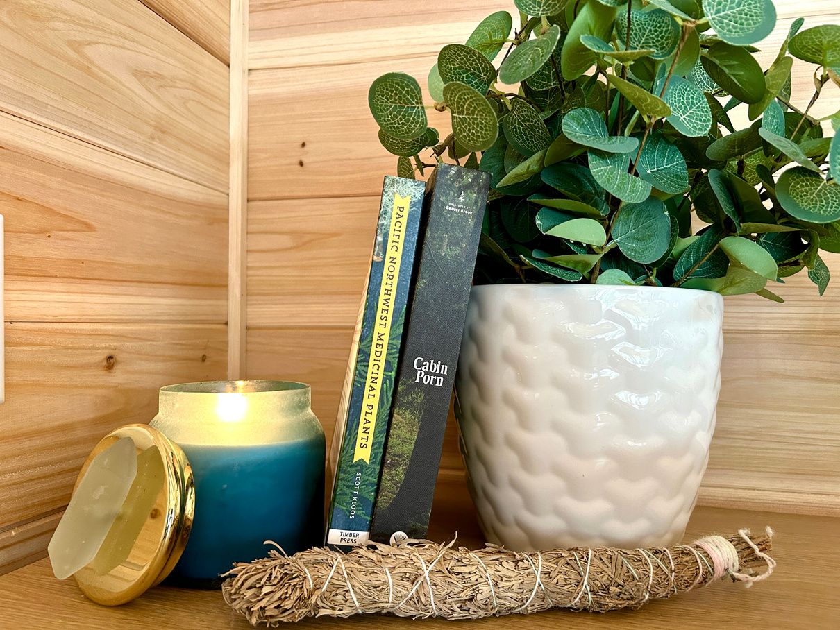 A candle, books, and greenery styled inside the Cedar Cabin