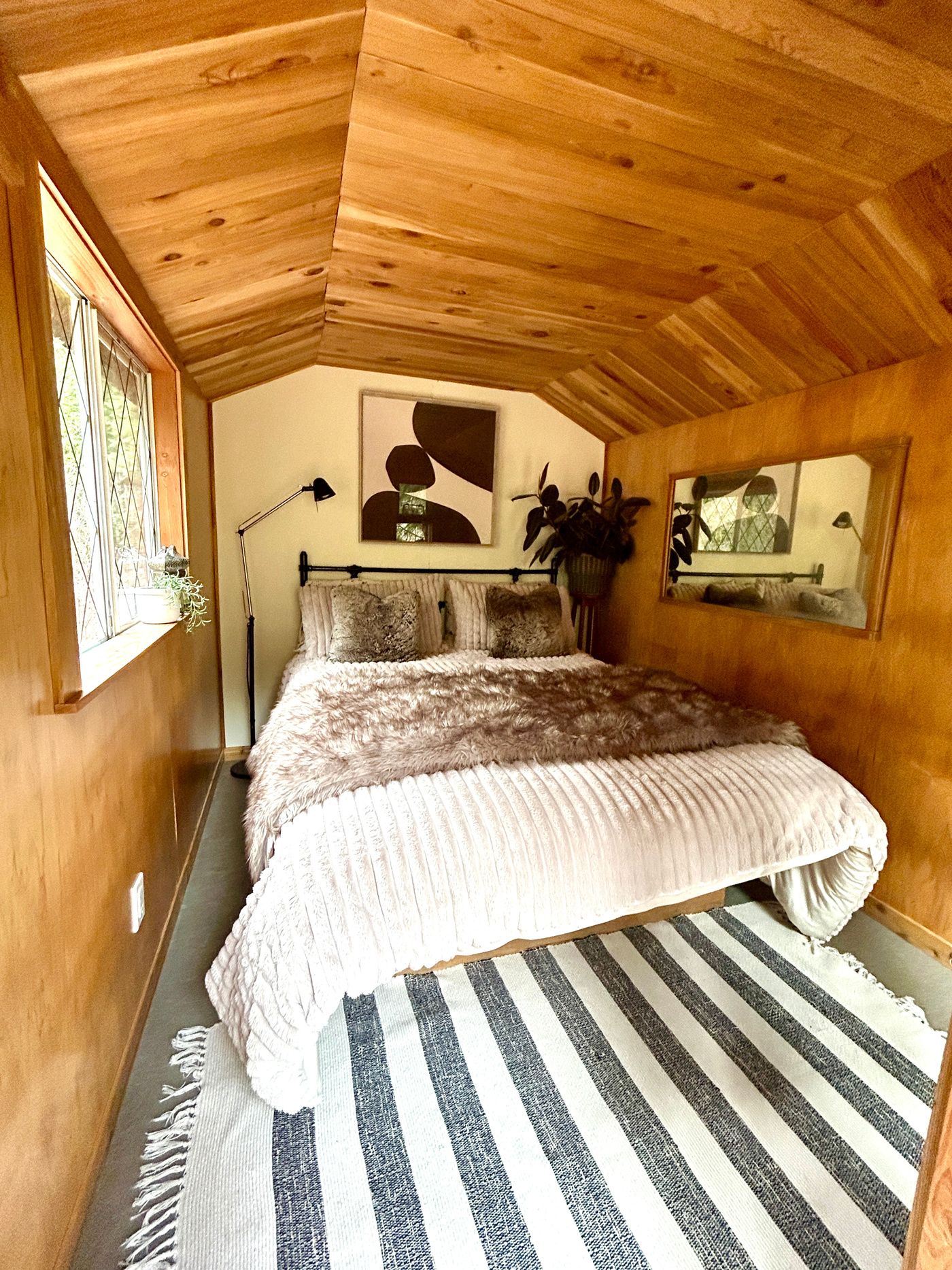 A cozy queen bed tucked under the Forest Cabin's wooden ceiling