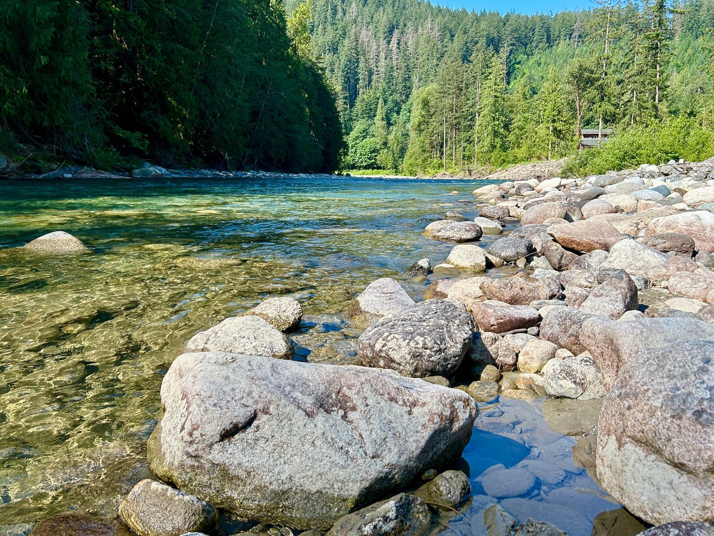 The Coquihalla River flowing past sunlit boulders at Watermark Eco-Retreat