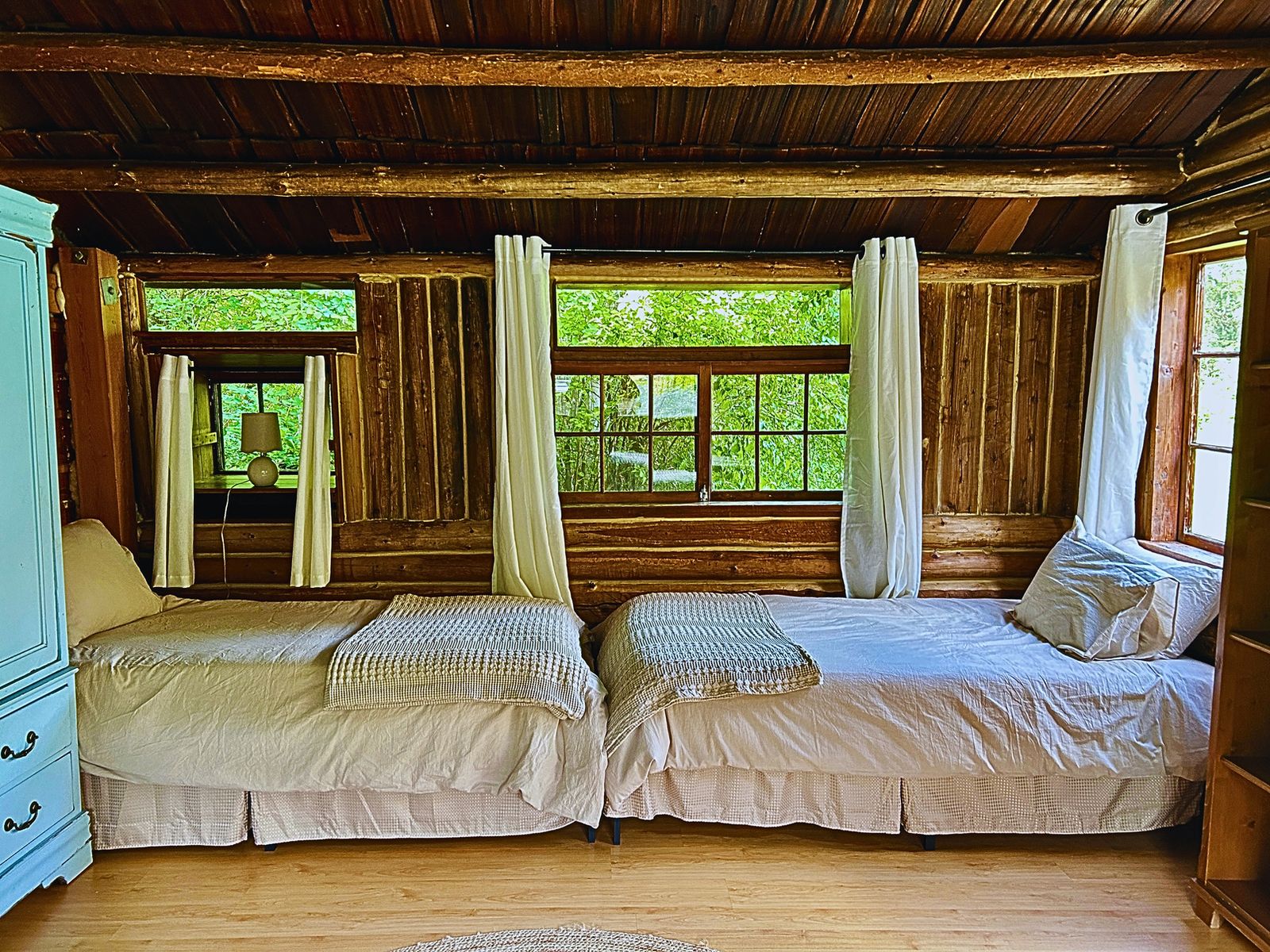 Single beds lined beneath bright windows in the Homestead Cabin