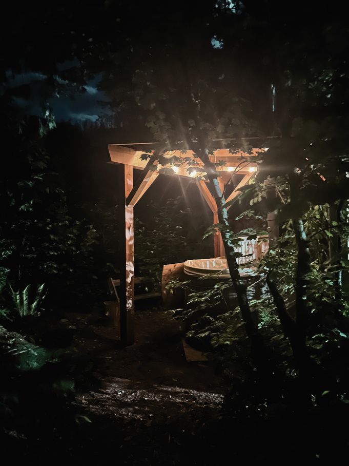 The wood-fired cedar hot tub glowing at night