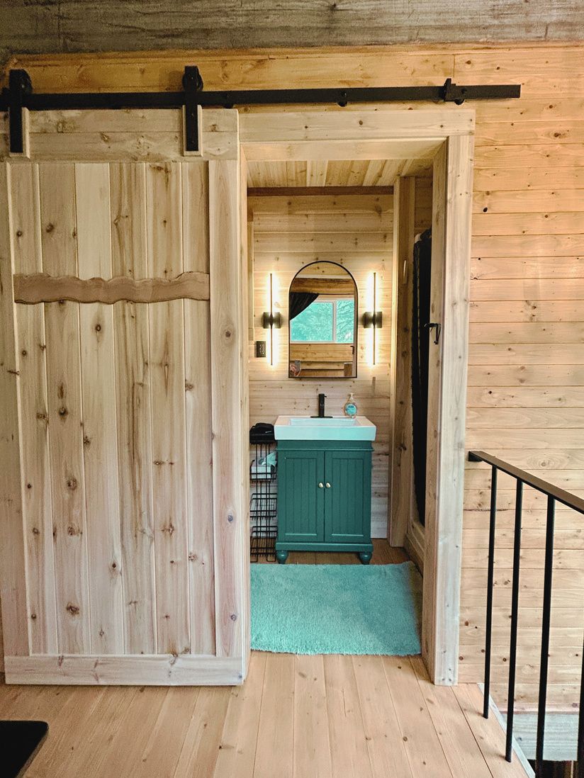 A cedar barn door opening to the Main House bathroom