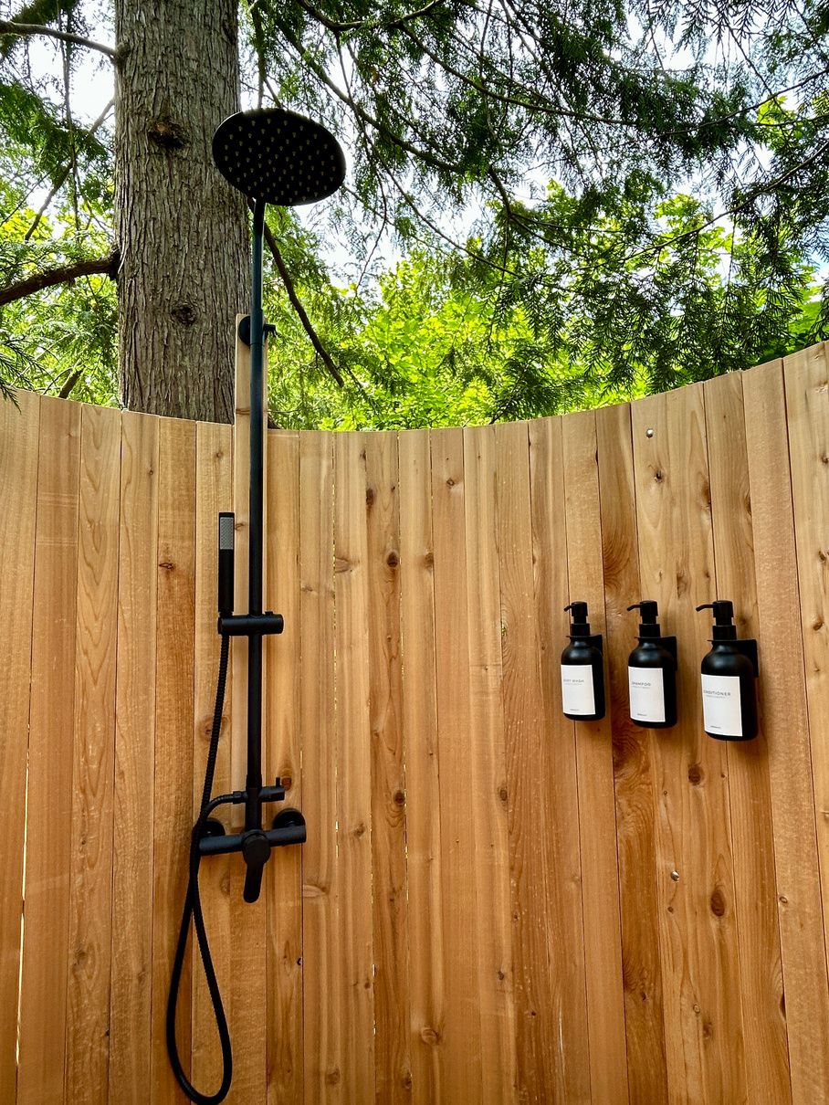 The cedar-enclosed outdoor shower beneath the forest canopy